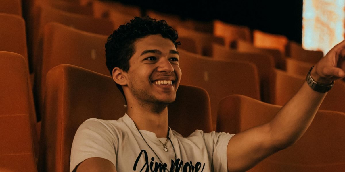 A person laughing while watching a movie, illustrating the emotional impact of well-crafted humor.