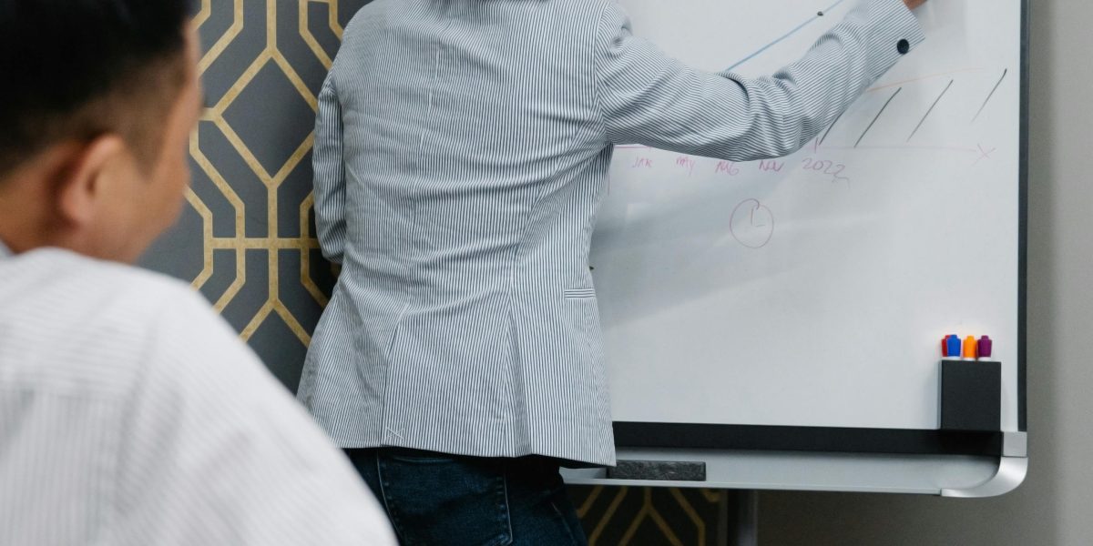 A team actively collaborating around a whiteboard, representing how empowering an audience or team leads to better engagement and problem-solving.