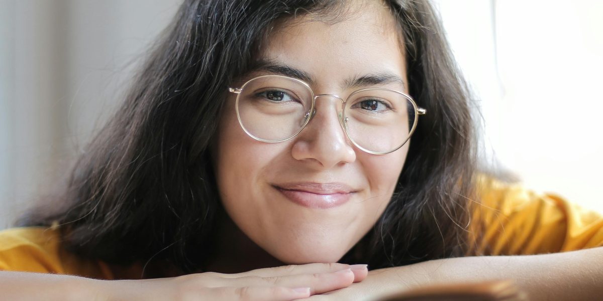 A thoughtful individual smiling while reading a book, representing the engagement and discovery fostered by intellectual and clever humor.