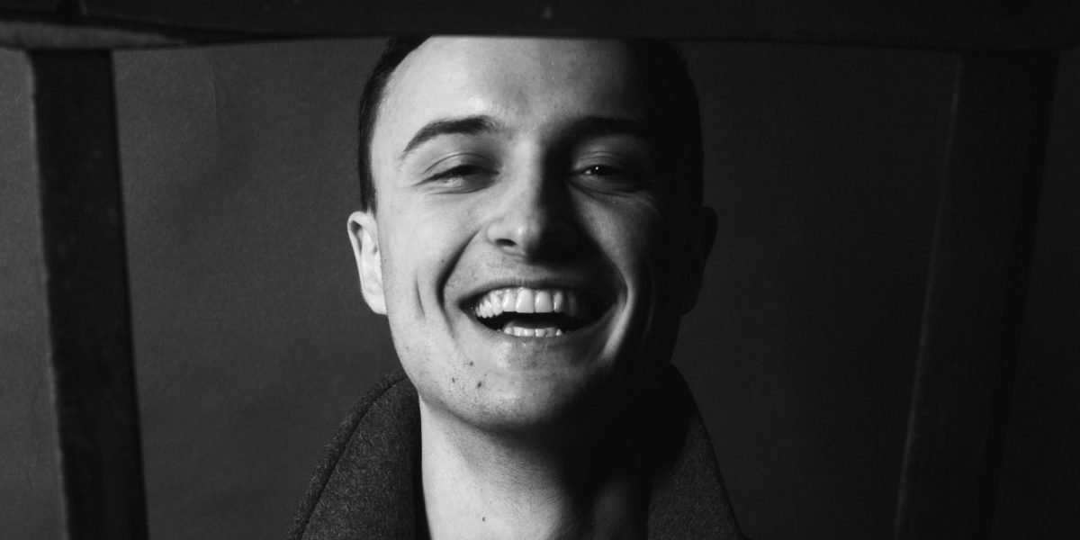 A person with a thoughtful expression, softly laughing, embodying an intellectually curious audience.