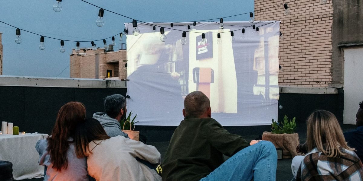 People gathered in a movie theater, laughing and enjoying a film together, representing mass audience appeal.